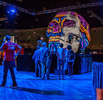 SIGGRAPH attendees observe an oversize, pink, blue, and orange patterned skull.