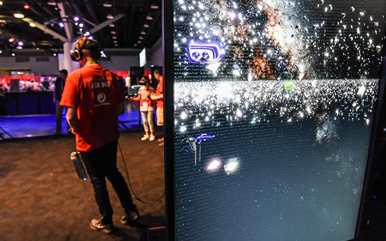 A SIGGRAPH volunteer wears a headset, through which he views a dark background filled with star-like sparkles.