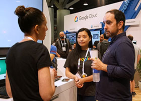 Three SIGGRAPH attendees in conversation at the Google Cloud exhibit booth.