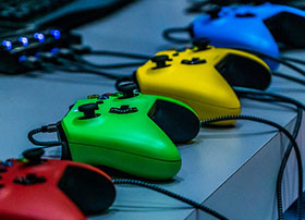 Red, green, yellow, and blue game controllers sitting on a counter top.